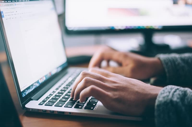 Hands typing on a keyboard writing a blog